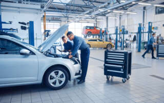 Mechanics examining the engine on a car in a garage.