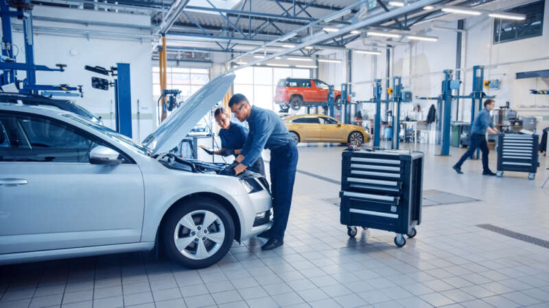 Mechanics examining the engine on a car in a garage.